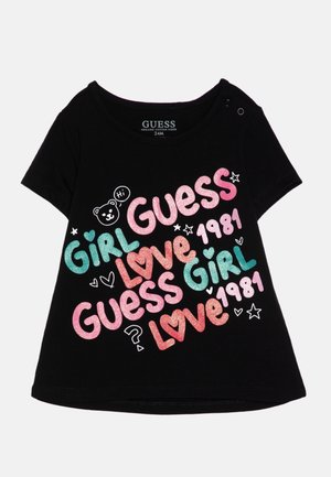 Sort toddler t-shirt med farverig glittertekst "Guess," "Girl," "Love," "1981," og små grafik af hjerter, stjerner og en bjørn, der siger "Hi."