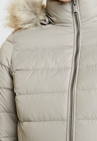 Beige pufferjack met horizontale gestikte textuur, voor met rits sluiting en afneembare nepbont kap.