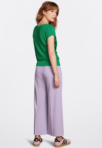 Grön rutad kortärmad tröja, bärs med högmidjade lavendel vida byxor och rosa sneakers med svarta detaljer.