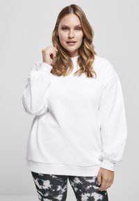 Felpa bianca con collo tondo, vestibilità comoda e maniche arricciate, abbinata a leggings tie-dye bianco e nero. Tessuto dalla texture liscia.