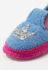 Blue felt slipper with a pink rubber sole, featuring a glittery silver crown design on the front. Soft texture and rounded shape.