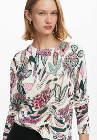 Maglione lavorato a maglia con una base crema e vivaci motivi floreali in rosa, verde e teal. Collo rotondo e maniche lunghe con polsini a coste.