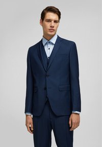 Veste de costume bleu foncé avec un revers cranté et deux boutons, associée à une chemise habillée bleu clair avec un col pointu et des détails de boutons.