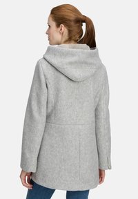 Cappotto di lana grigio con un grande cappuccio, silhouette su misura e tasche laterali; texture morbida con una leggera lucentezza, design di lunghezza media.