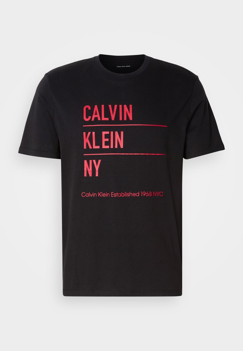 Camiseta de algodón negra con texto rojo en negrita: "CALVIN KLEIN NY" y "Calvin Klein Established 1968 NYC" con cuello redondo.