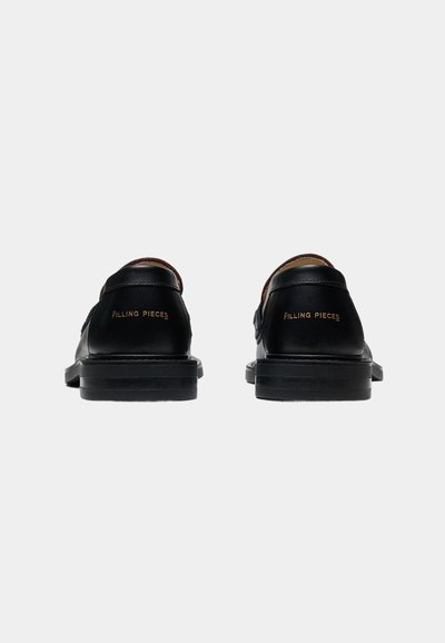 Ζευγάρι μαύρα δερμάτινα loafers με ανάγλυφο κείμενο "Filling Pieces" στη φτέρνα, εμφανίζονται από πίσω σε λευκό φόντο.