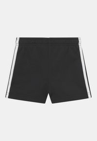 Pantalones cortos negros con una cintura elástica, con dos rayas laterales blancas. Hechos de una tela suave con una textura uniforme.