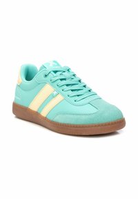 Zapatilla de color azul aqua con acentos amarillos, que cuenta con una parte superior de textil suave, lengua acolchada y una suela de goma texturizada.