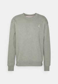 Sudadera gris de cuello redondo con mangas largas y un pequeño logo de Jumpman en blanco en el lado izquierdo del pecho, presentada sobre un fondo blanco.