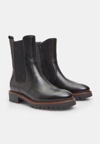 Bocanci din piele neagră ankle, cu panouri elastice pe laterale, vârf rotund și talpă din cauciuc cu crampoane. Includ o fermoar discret pe o parte.
