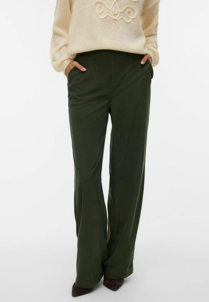 Zielone szerokie spodnie o gładkiej fakturze, z bocznymi kieszeniami i elastycznym paskiem, zestawione z kremowym swetrem.