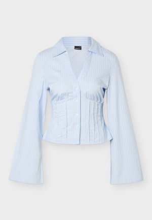 Ανοιχτό μπλε μπλούζα με μακριά μανίκια και λεπτές κάθετες ρίγες, γιακάς V, κουμπιά στο μπροστινό μέρος και εφαρμοστή μέση με λεπτομέρειες.