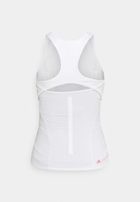 Bílý sportovní top bez rukávů s designem typu racerback, síťovinovými panely a vertikálním švem na zadní straně. Červený detail loga.