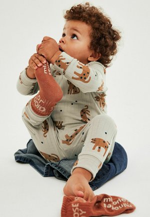 Bomuldspyjamasæt i lysegrå med brune dyreprints. Ribbede tekstur, lange ærmer og matchende brune sokker med hvid tekst.