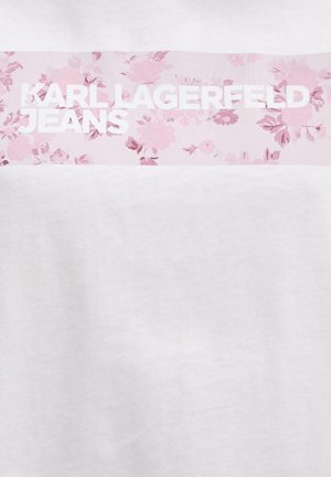 Tissu blanc avec une bande florale rose en haut, avec un texte blanc en gras "KARL LAGERFELD JEANS."