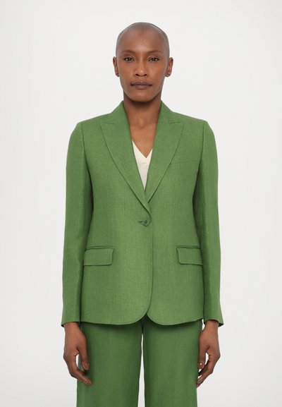Blazer verde cu rever întrerupt, închidere cu un singur nasture și două buzunare frontale, asortat cu pantaloni corespunzători și un top de culoare deschisă sub acesta.