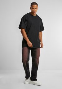 Camiseta negra de gran tamaño hecha de algodón, combinada con jeans de mezclilla oscura que presentan un degradado de color, complementada con zapatillas blancas.