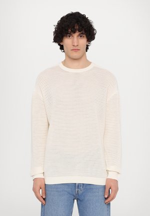 Light beige sweater with a textured pattern, long sleeves, and ribbed cuffs. Made from breathable material, features a crew neckline.