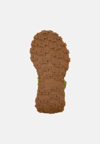 Kinder-Schuhsohle aus strukturiertem, robustem braunen Gummi mit ausgeprägten Stollen für Traktion und einem "Camper"-Logo.