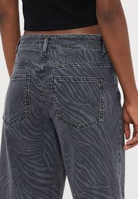 Sorte zebra-mønstret jeans med høj talje, fem-lommer design og tonale syninger. Materialet er denim med en glat tekstur.