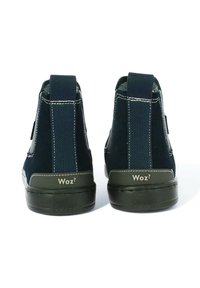 Scarpe alla caviglia in suede blu navy con una finitura testurizzata, pannelli laterali elasticizzati e suola in gomma. Presentano il marchio "Woz²" e dettagli di cucitura bianca.