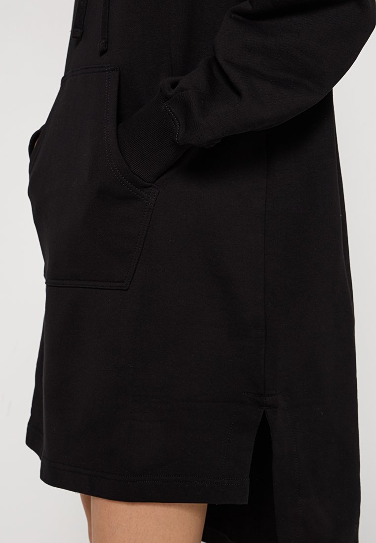 Zwarte, casual hoodie jurk gemaakt van zacht materiaal. Heeft een voorvak, zijdelingse splits en ribgebreide mouwboorden voor een comfortabele pasvorm.