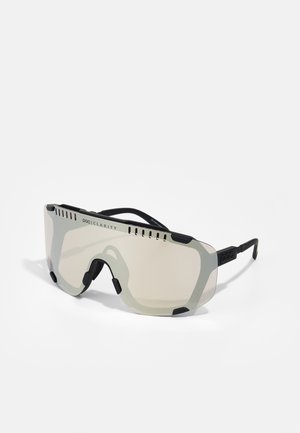 Ochelari de soare cu un design mare, tip wraparound, dispune de lentile gri translucide, accente negre și canale de ventilație pe partea de sus.