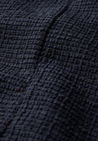 Gewebter Stoff in dunkelmarineblau mit einem strukturierten, erhabenen Muster. Die Oberfläche wirkt weich und leicht samtig, was Tiefe und Interesse erzeugt.