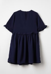 Granatowa sukienka z krótkimi falbaniastymi rękawami, falbaniastą talią i zapięciem na plecach w kształcie łezki. Wykonana z gładkiego, lekkiego materiału.