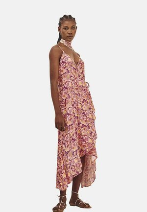 Vestido largo en rosa con estampado floral púrpura, escote en V, dobladillo asimétrico y tirantes finos. Confeccionado en una tela ligera y fluida.