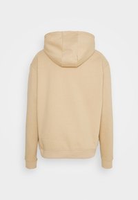 Beige huvtröja med känguruficka, ribbade ärmslut och en mjuk textur. Baksidan har en enkel, ren design utan utsmyckningar.