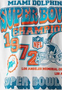 Camiseta blanca con texto en negrita azul y naranja: "Miami Dolphins Campeones del Super Bowl 1972", con gráficos de casco de fútbol y el logo de un delfín.