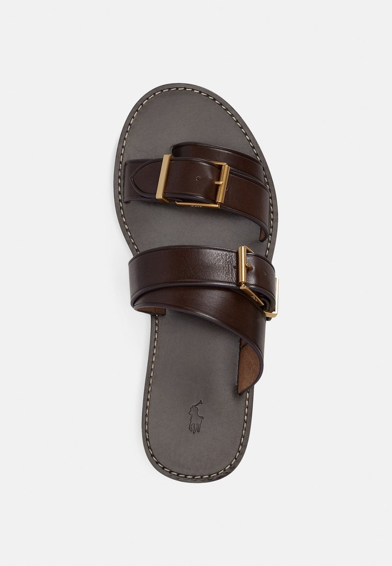 Brown leather sandal with two adjustable straps and gold buckles. Features a smooth sole and contrasting white stitching along the edges.