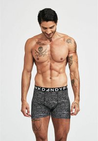 Boxers noirs avec un motif en forme de circuit en blanc, dotés d'une ceinture large portant l'inscription "PINKDANDY". Le matériau semble doux et ajusté.