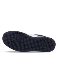 Sneaker outsole in navy rubber with a textured pattern, circular grip detail, and a logo embossed on the side for traction and durability.