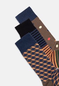 Tre par sokker: mørkeblå med et geometrisk mønster, sorte og brune med polka prikker og striber i jordfarver. Materiale af bomuldsblanding.