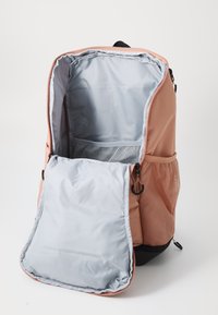 Mochila con un exterior rosa suave, forro interior gris, bolsillos laterales de malla y una gran apertura para un fácil acceso. Material texturizado.