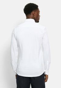 Weißes Langarmhemd mit Standardkragen, glatter Textur und geknöpften Manschetten, mit geradem Schnitt und Rückenpasse.