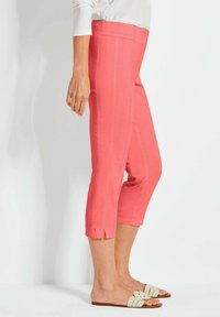 Koraal kleurige capri broeken met een slim fit design, zijsplitsingen aan de zoom en een gladde textuur. Draagt met lichtgekleurde instap sandalen.