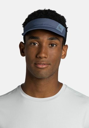 Man with dark curly hair wearing a blue visor and a white crew-neck shirt, facing forward with neutral expression on light background.
