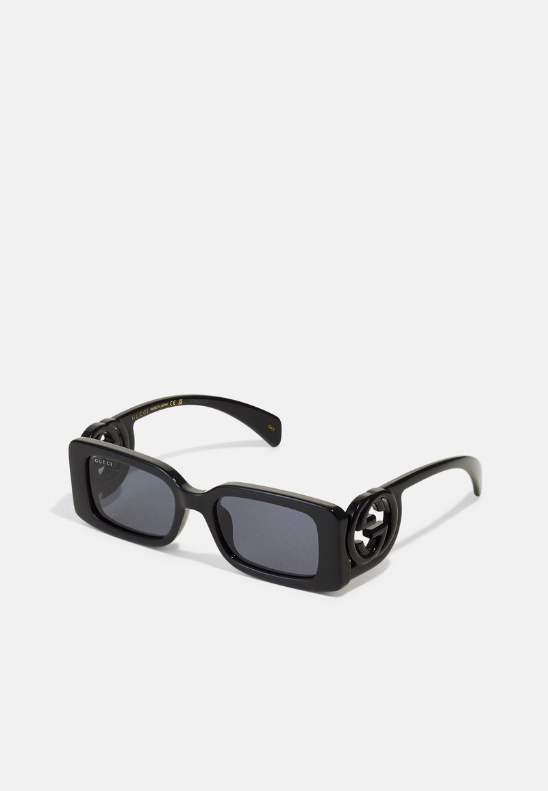 Gafas de sol rectangulares negras con lentes oscuros, que presentan un hardware intrincado en las patillas y un acabado brillante y elegante.