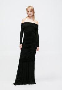 Czarna sukienka bez ramiączek z długim rękawem, o fakturze marszczonej w całej powierzchni, zwiewnym odcinku i dopasowanym kroju górnej części.