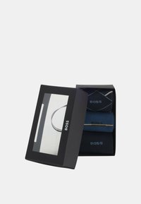 Scatola regalo contenente tre paia di calzini in tonalità di blu, con una combinazione di design a tinta unita e a fantasia, con il marchio BOSS ben visibile.