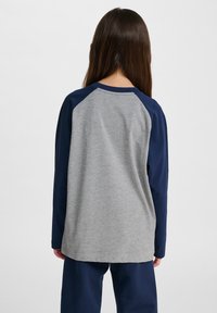 Langärmliges Shirt mit grauem Körper und navyblauen Raglanärmeln. Aus Baumwollmaterial, runder Halsausschnitt und gerade geschnittene Säume.