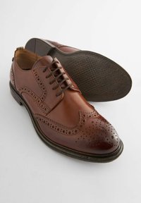 Chaussures habillées en cuir marron avec une finition lisse, des détails en brogue, un design à lacets et une semelle en caoutchouc texturée.