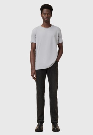 Grå kortærmet t-shirt med rund hals, parret med sorte slim-fit jeans og sorte støvler. Simpelt design, minimal detaljer.