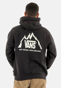 Sudadera negra hecha de tela de mezcla de algodón que presenta un gráfico de montañas blancas y el texto "VANS OFF THE WALL EXPLORATION" en la parte posterior.