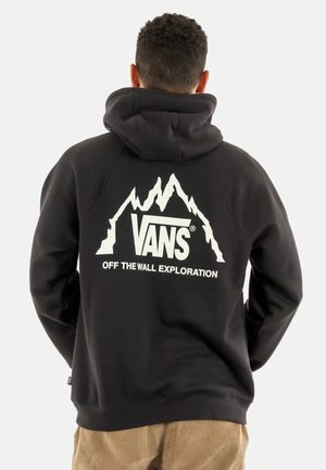 Sudadera negra hecha de tela de mezcla de algodón que presenta un gráfico de montañas blancas y el texto "VANS OFF THE WALL EXPLORATION" en la parte posterior.