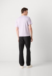Lilac short-sleeve t-shirt with a round neckline, paired with black pants. The shirt has a smooth texture and a relaxed fit.