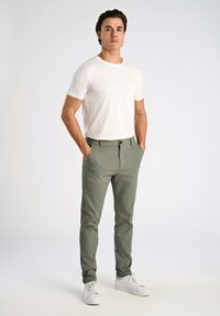 Helle graue Hose mit maßgeschneidertem Schnitt und strukturiertem Stoff, kombiniert mit einem schlichten weißen T-Shirt und weißen Sneakers. Präsentation eines lässigen Outfits.